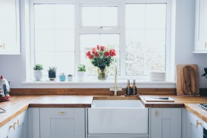 Modern and bright domestic kitchen with succulent plants, herbs and  roses on window sill